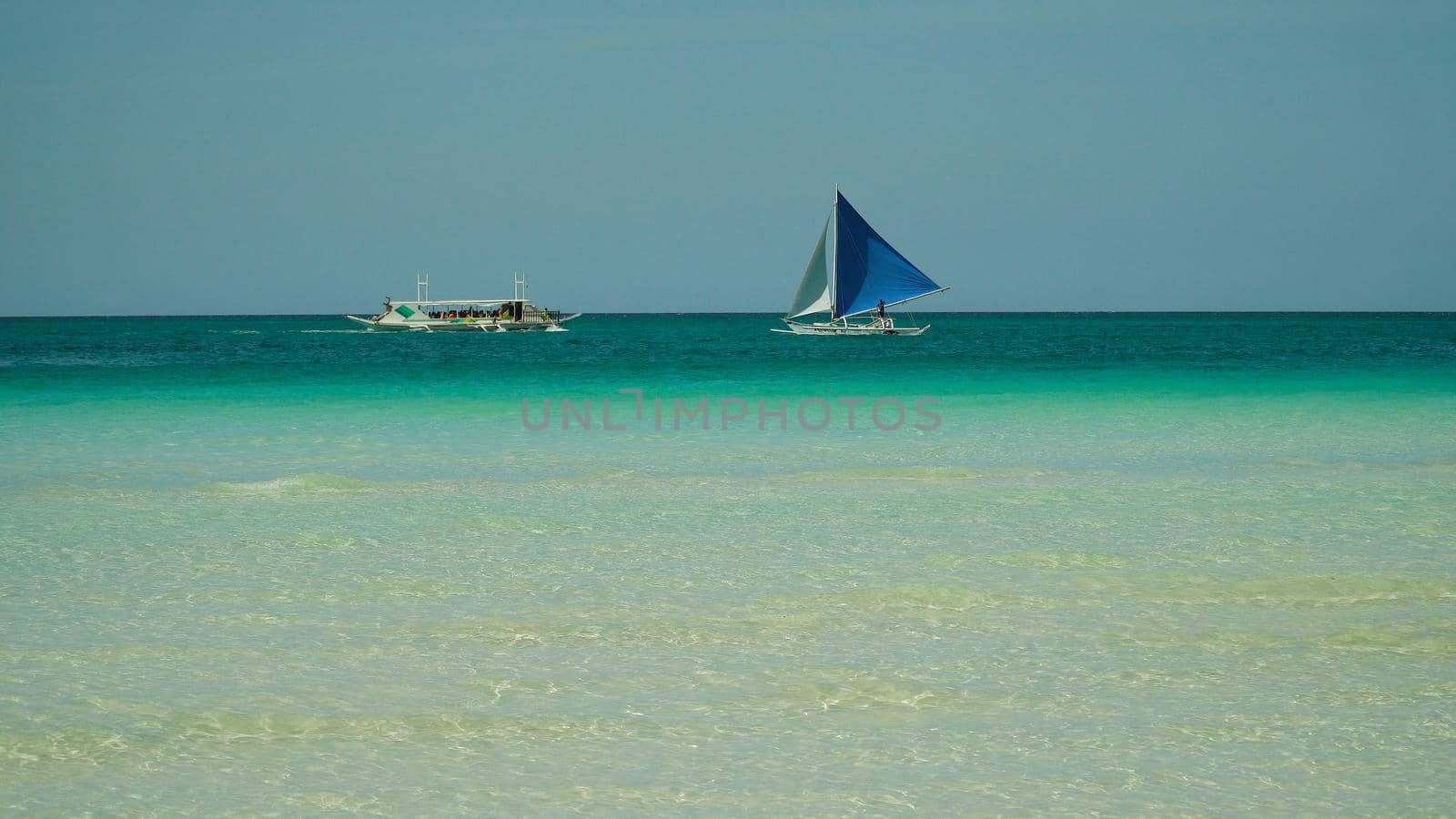 Seascape: tropical beach and sailing yacht in crystal clear turquoise water. Summer and travel vacation concept. Boracay, Philippines