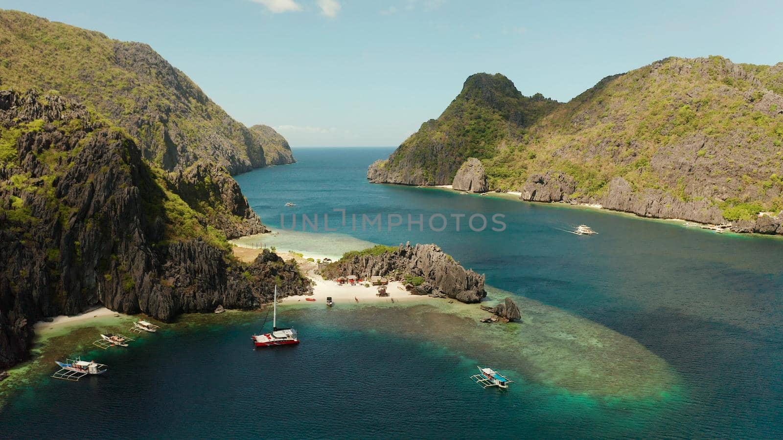 Tropical landscape bay with beach and clear blue water surrounded by cliffs, aerial drone. El nido, Philippines, Palawan. Seascape with tropical rocky islands, ocean blue water. Summer and travel vacation concept