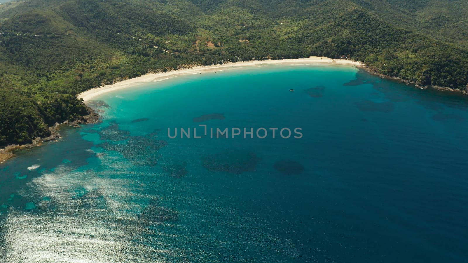 Aerial drone of beautiful tropical beach in cove with blue lagoon and turquoise water. Seascape with sea, sand, palm trees. Nagtabon, Palawan, Philippines. Summer and travel vacation concept