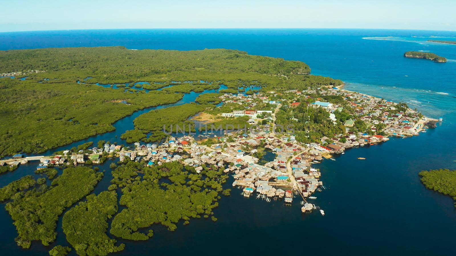 City in wetlands and mangroves on the ocean coastline aerial view. Siargao island, Philippines.