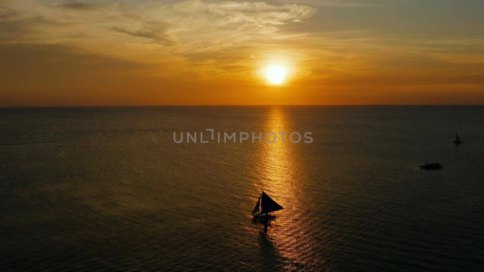Colorful sunset above the sea surface with sailing yachts, aerial view Boracay, Philippines. Reflected sun on a water surface. Sunset over ocean. Seascape, Summer and travel vacation concept