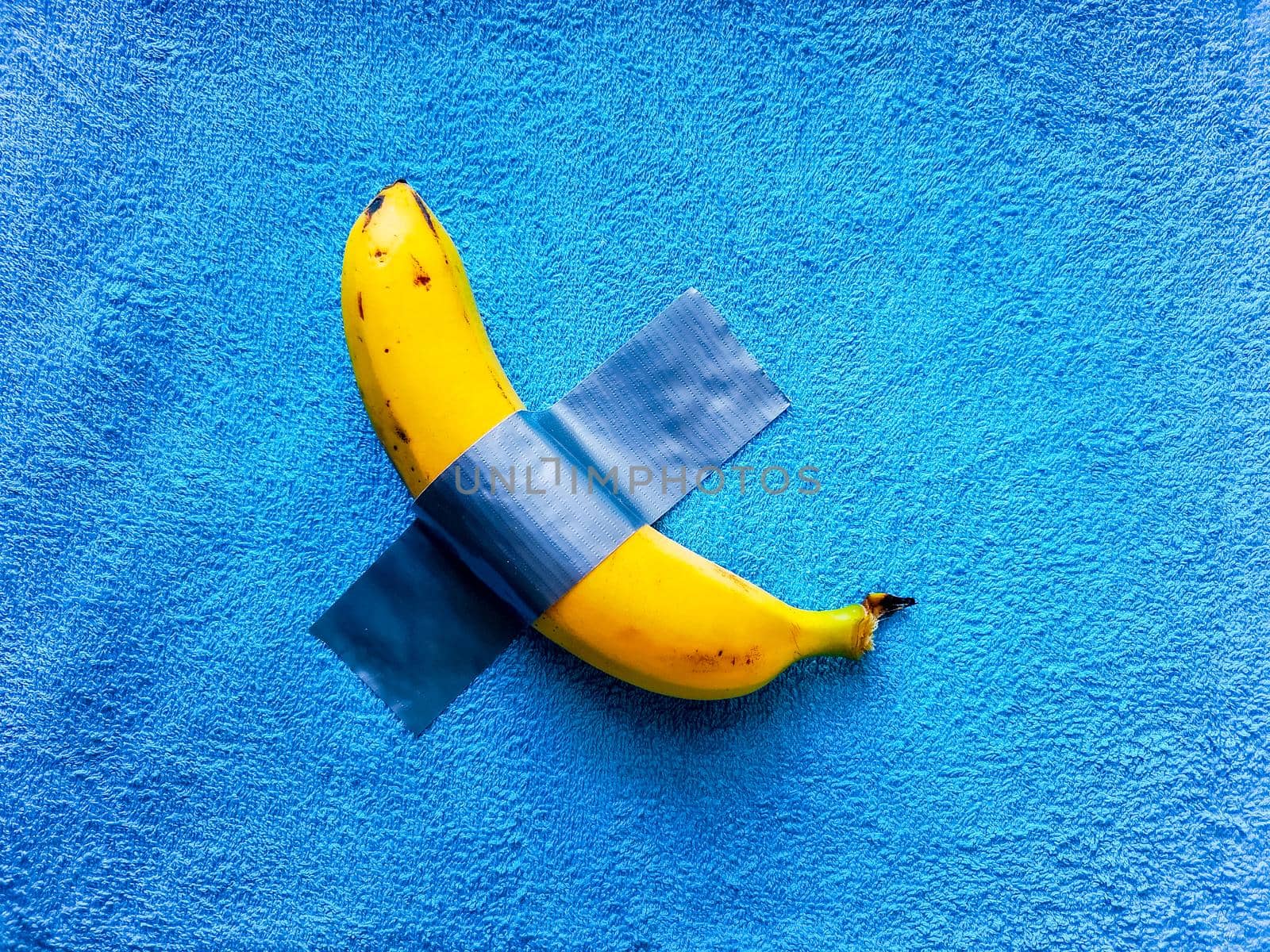 Yellow banana lie taped on blue towel