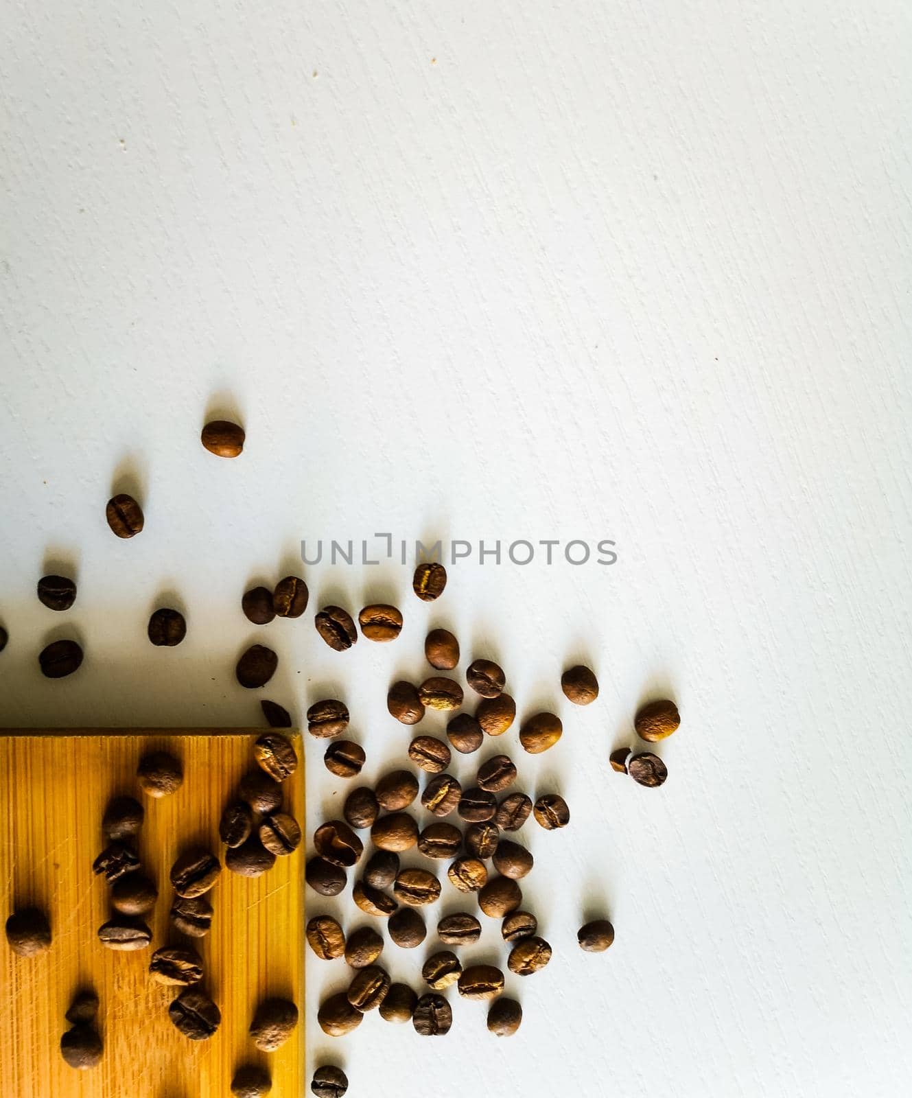 Coffee beans lie on wooden board and white table by Wierzchu