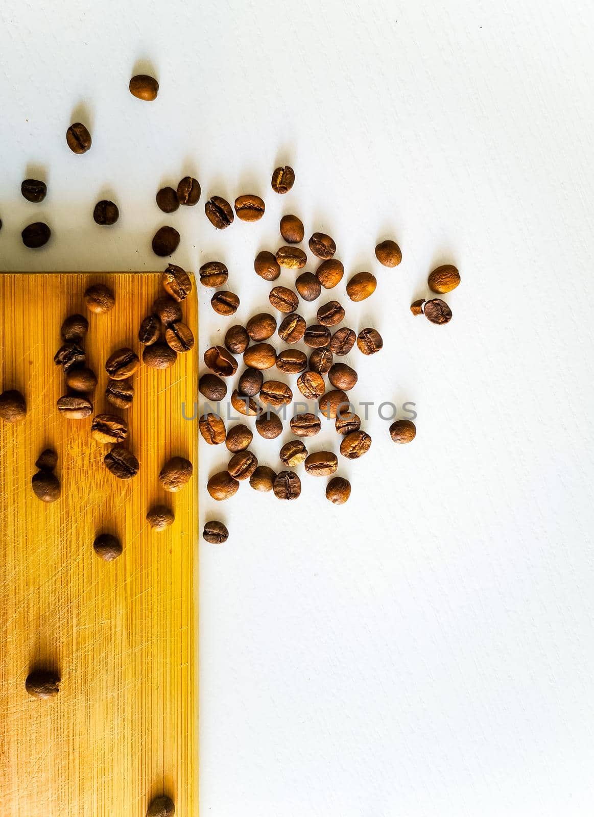 Coffee beans lie on wooden board and white table by Wierzchu