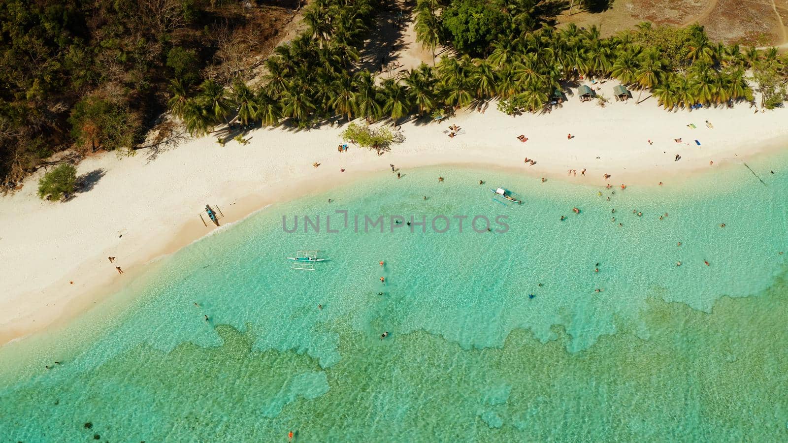 aerial seascape tourists enjoy tropical beach. tropical island with sand beach, palm trees. Malcapuya, Philippines, Palawan. Tropical landscape with blue lagoon, coral reef