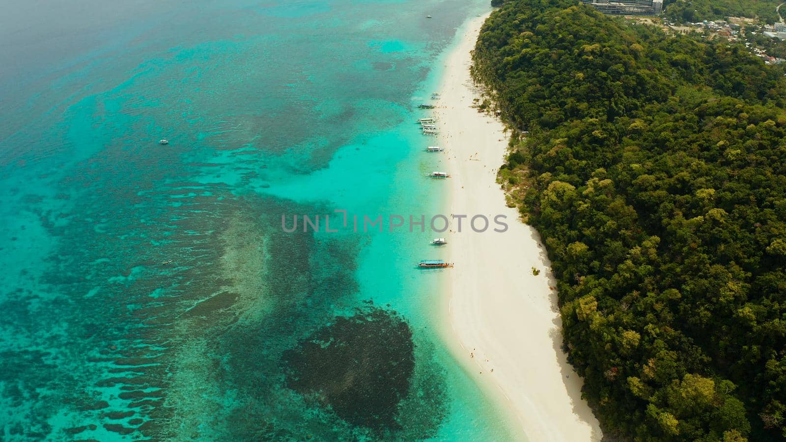 Sandy beach and turquoise water in the tropical resort of Boracay, Puka shell beach, Philippines aerial view. White beach with tourists. Summer and travel vacation concept.