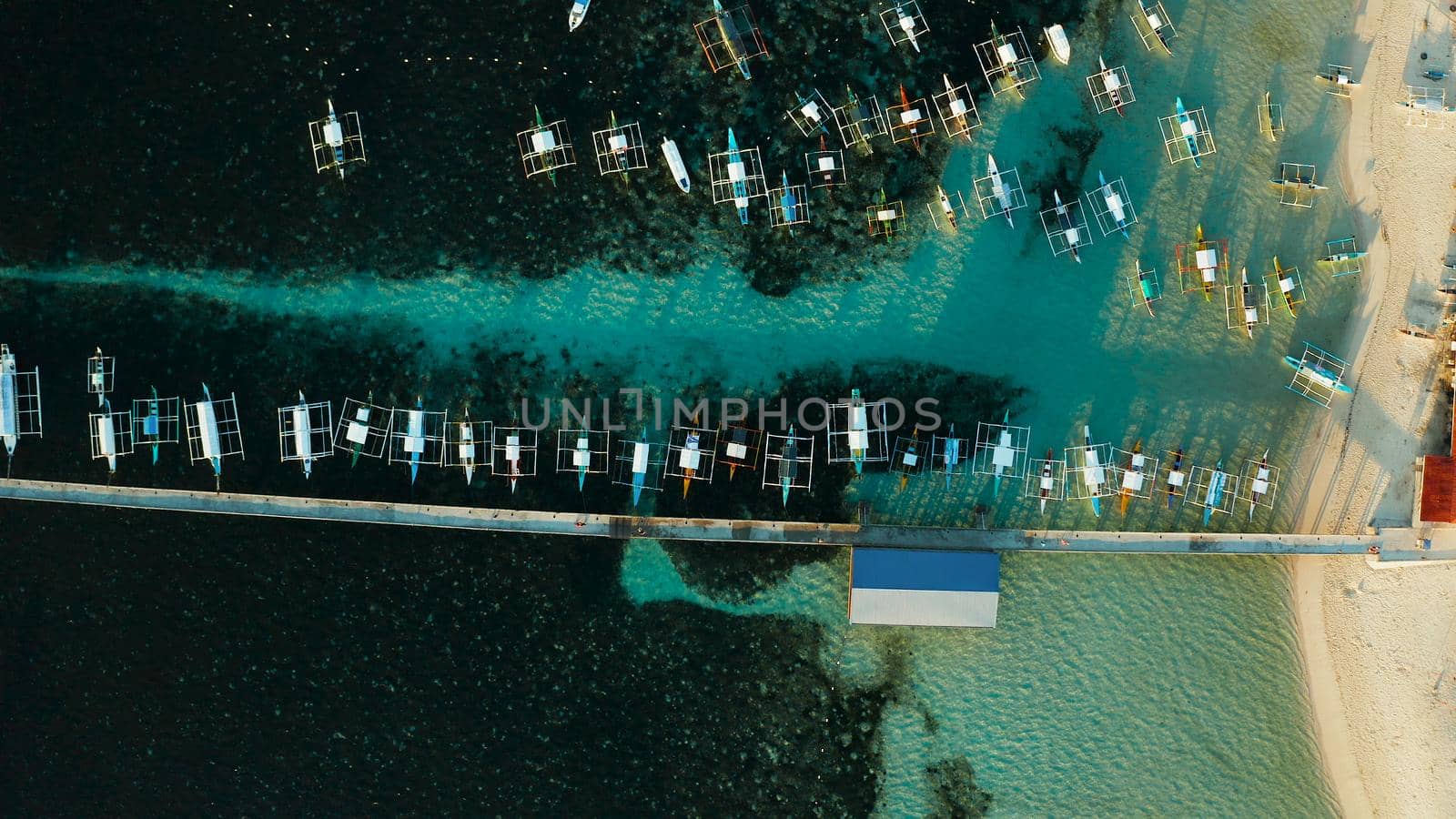 Long pier with moored boats in the morning, aerial view. General Luna, Siargao island.