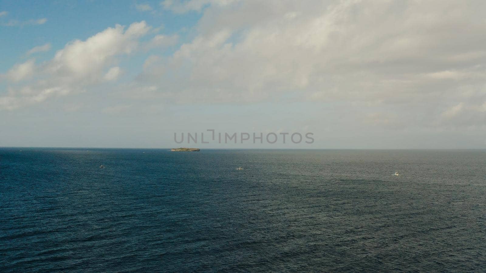 Sea surface with waves against the blue sky with clouds, aerial view. Water cloud horizon background. Blue sea water with small waves against sky.