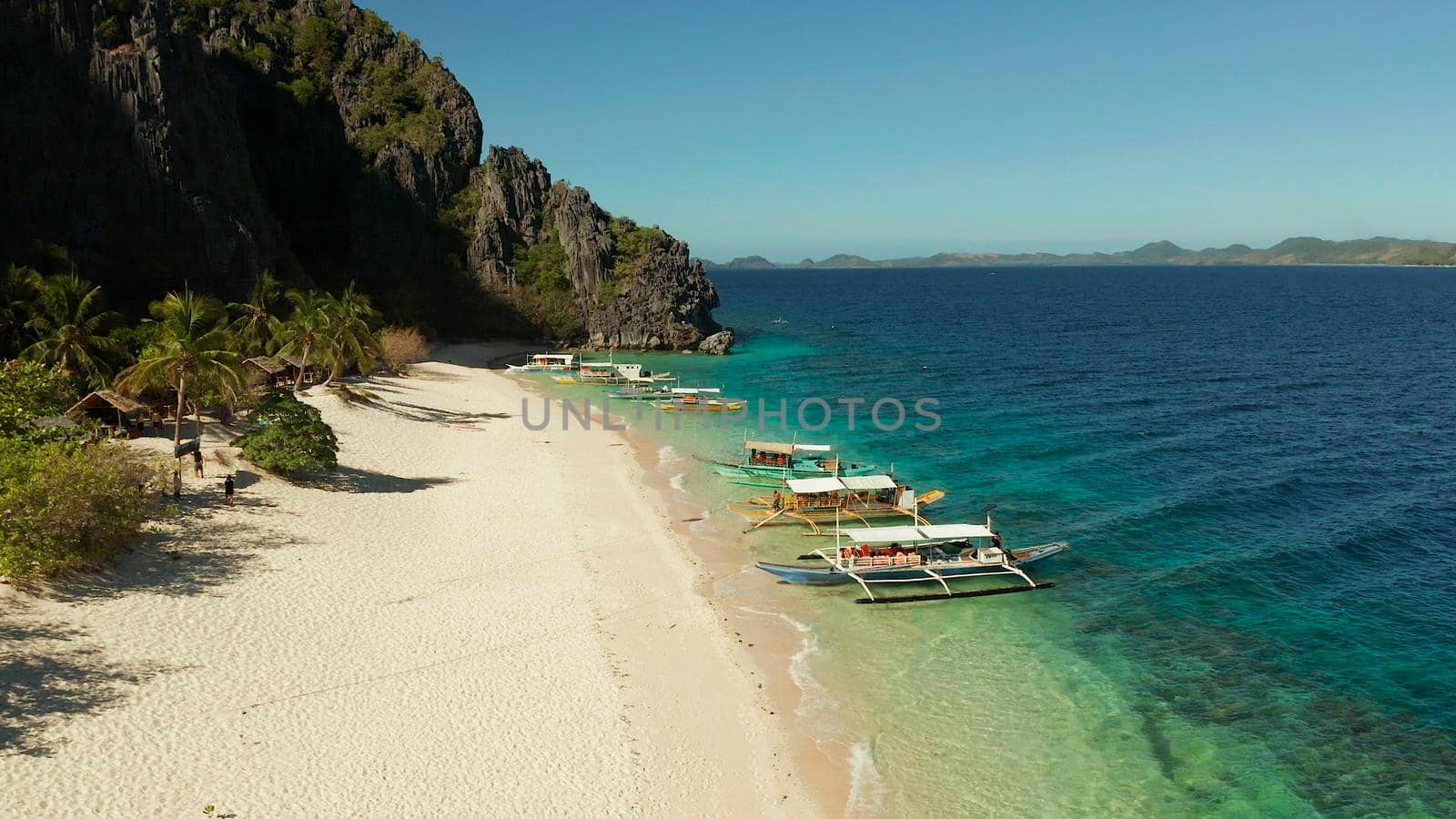 aerial view island with tropical sandy beach and palm trees. Malajon Island, Philippines, Palawan. tourist boats on coast tropical island. Summer and travel vacation concept. beach and blue clear sea water