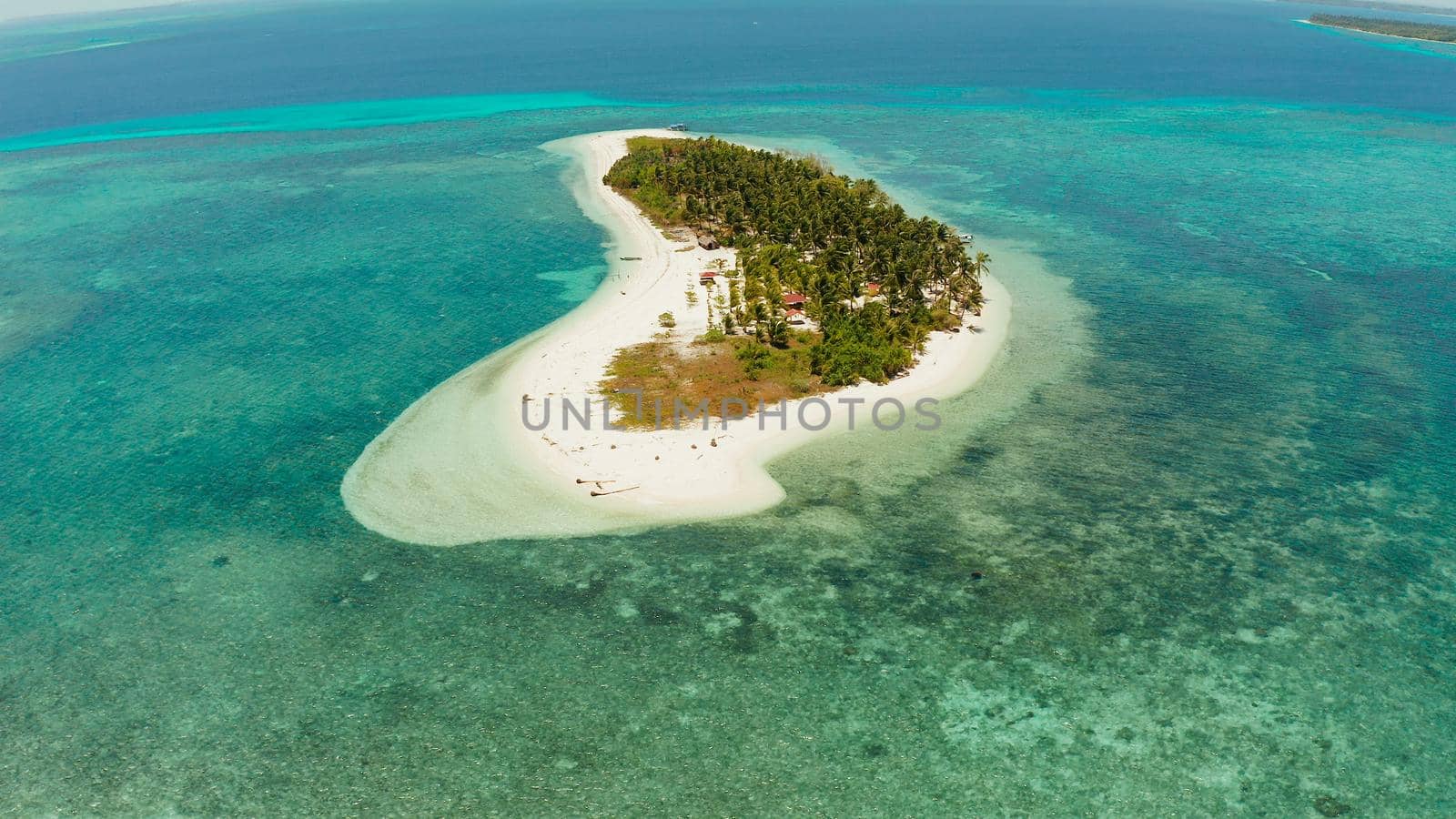 Travel concept: tropical island on an atoll with beautiful sandy beach by coral reef from above. Canimeran Island and coral reef. Summer and travel vacation concept.