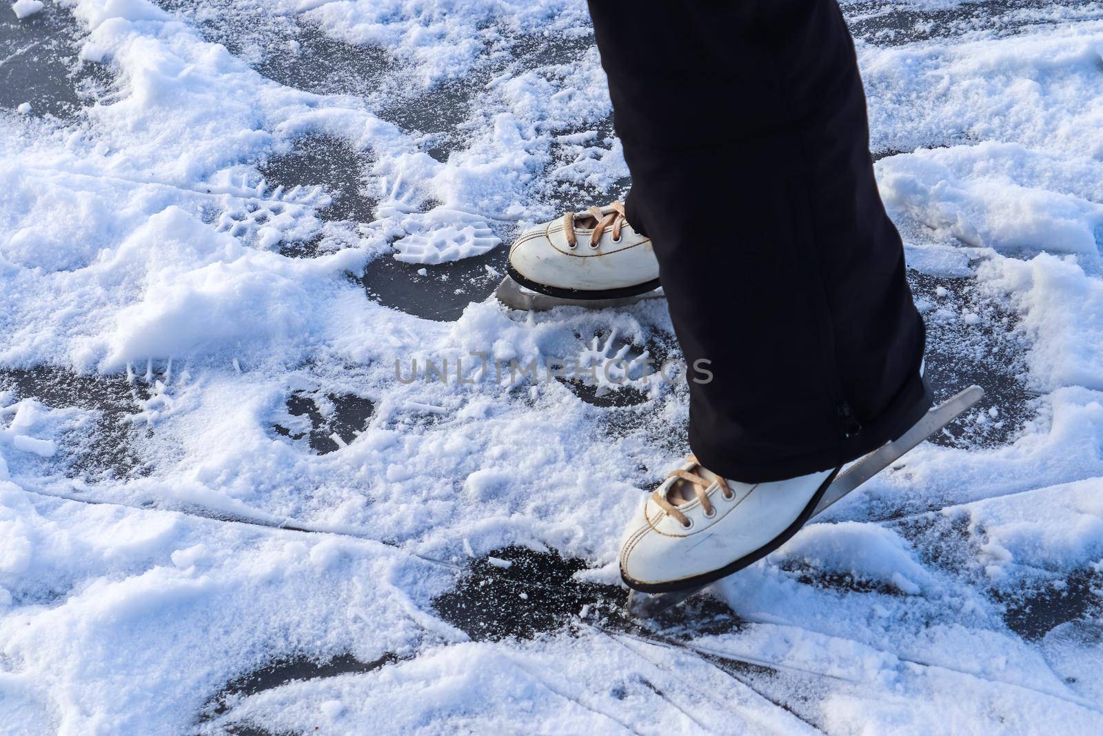 Close up on womans feet wearing ice skating boots and standing on ice. by MP_foto71
