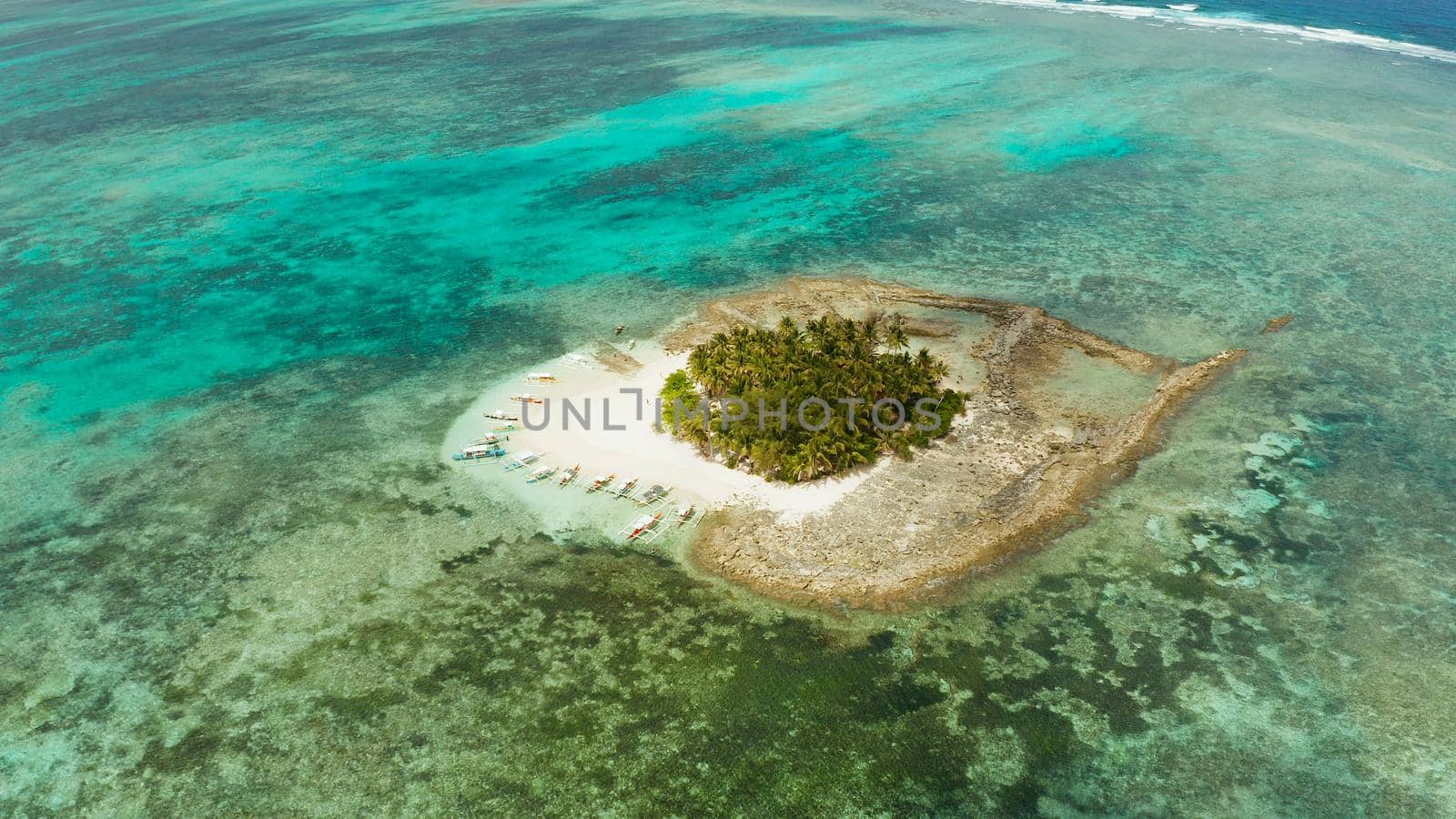 Aerial view of sandy beach with tourists on tropical island with palm trees and turquoise water. Guyam island, Philippines, Siargao. Summer and travel vacation concept