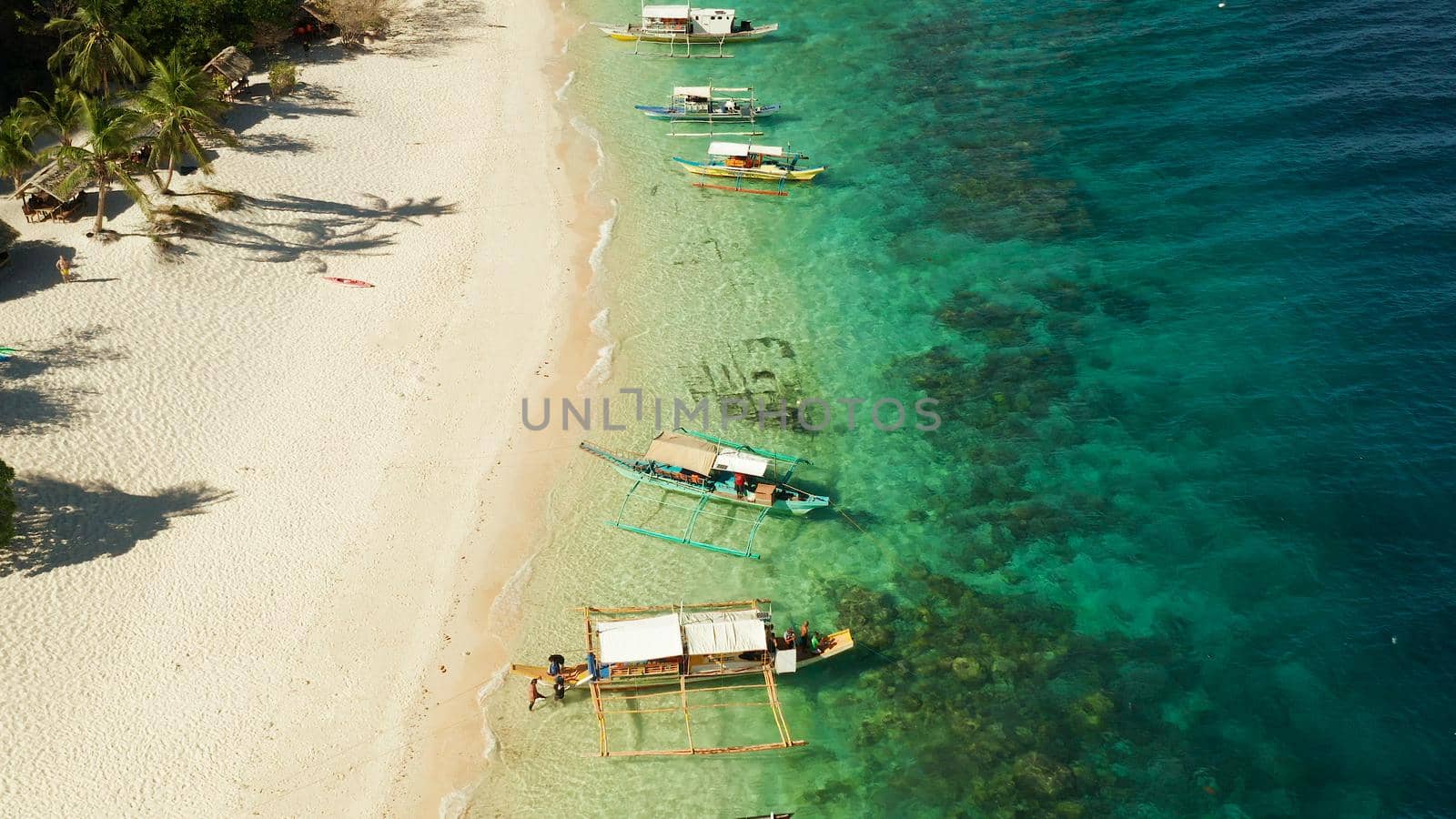 aerial view island with tropical sandy beach and palm trees. Malajon Island, Philippines, Palawan. tourist boats on coast tropical island. Summer and travel vacation concept. beach and blue clear sea water