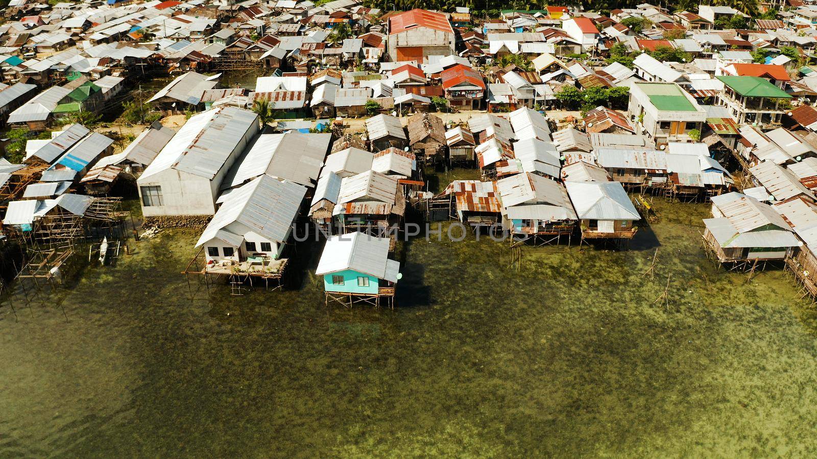 Fishing village with boats and slums with wooden houses, aerial drone. Dapa, Siargao, Philippines.