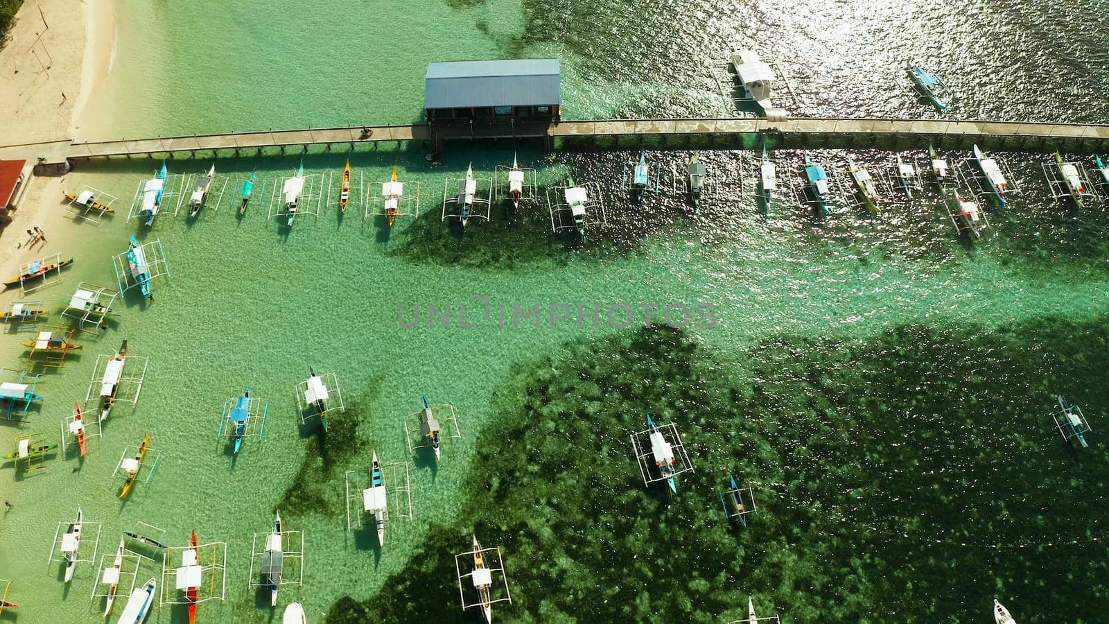 Long pier with moored boats on the beach, aerial view. General Luna, Siargao island.