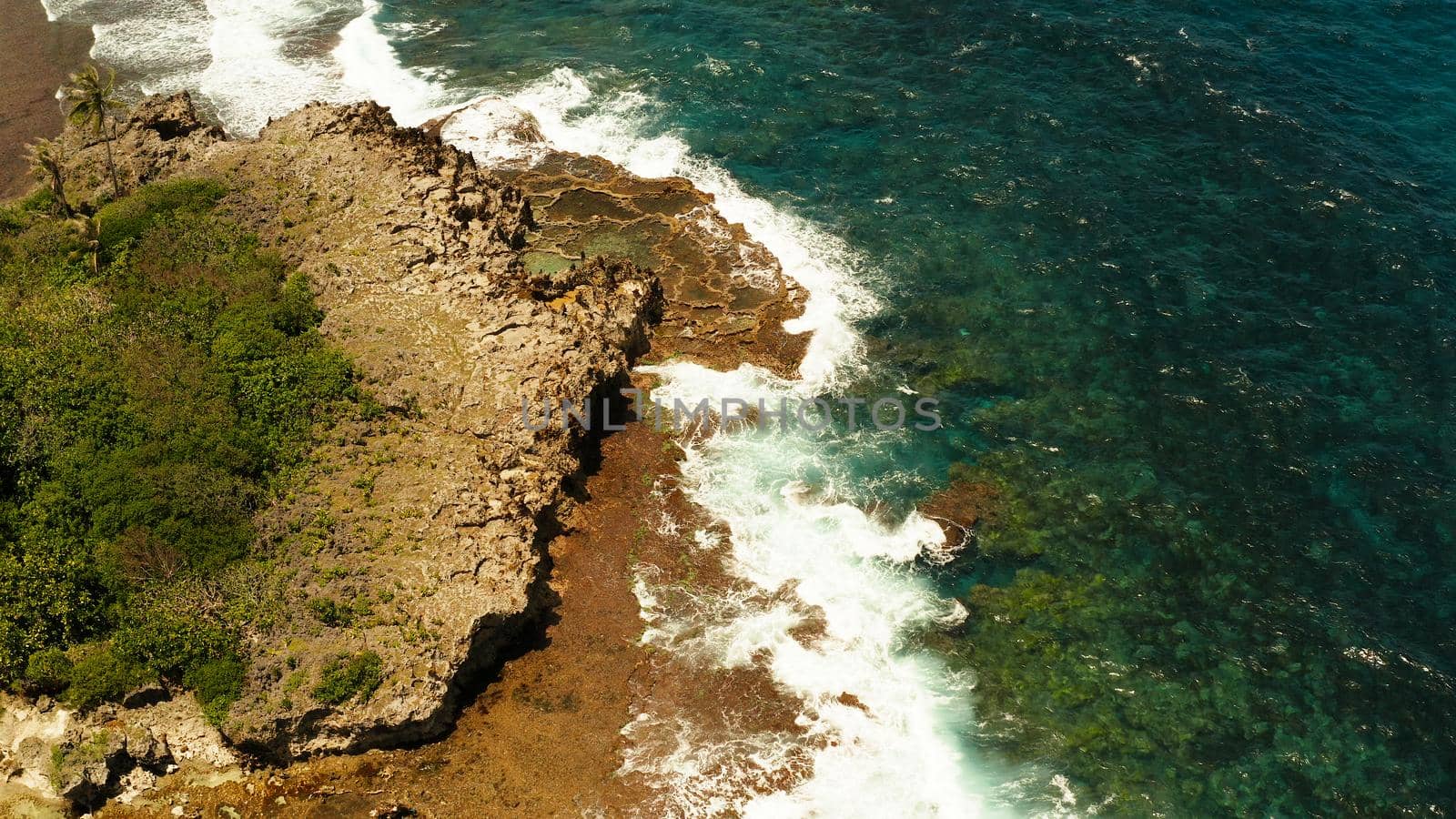 Ocean waves crashing on rocky shore from above. Siargao, Philippines. Summer and travel vacation concept