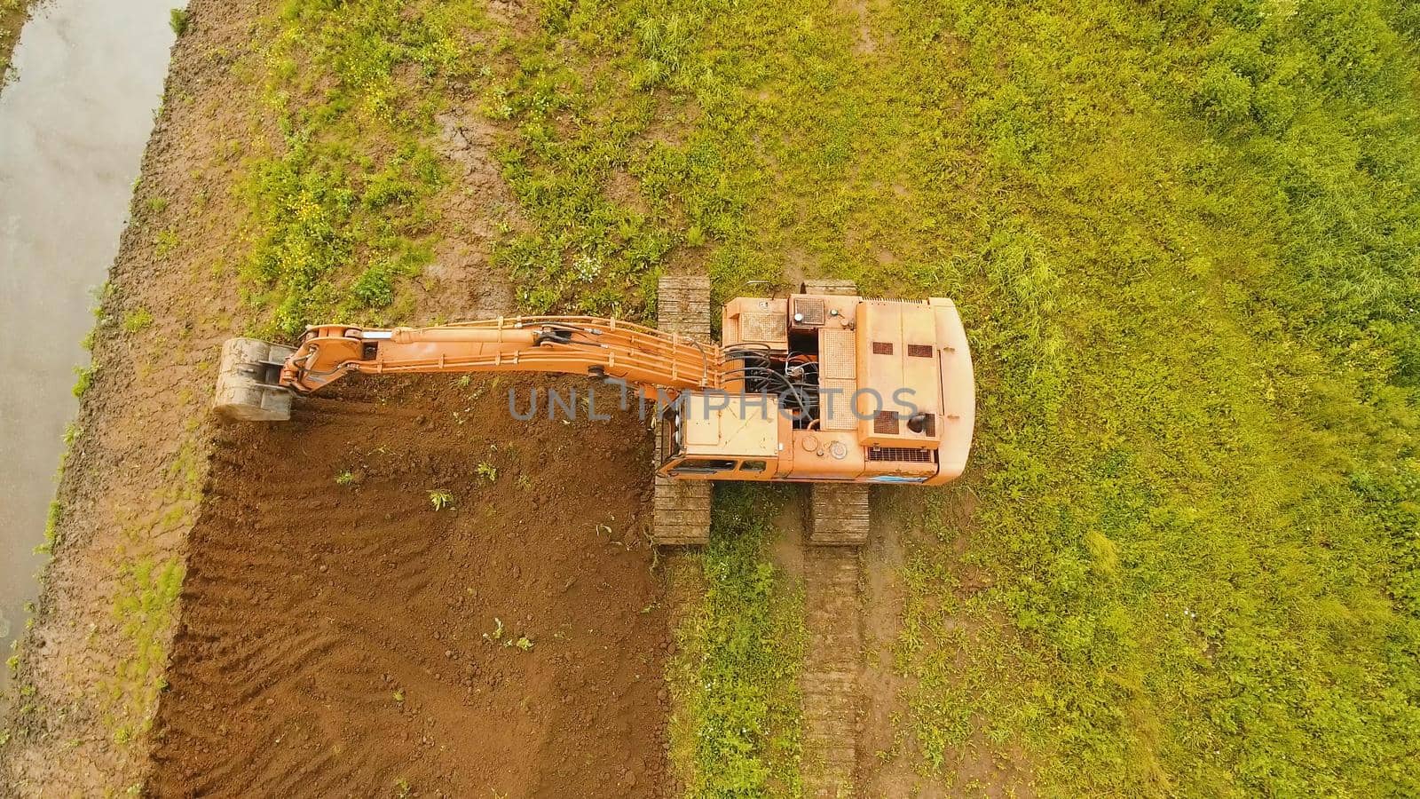 Excavator is digging an irrigation canal. Aerial view:Excavator digging a deep trench.excavator is digging an drainage canal in the agricultural field.
