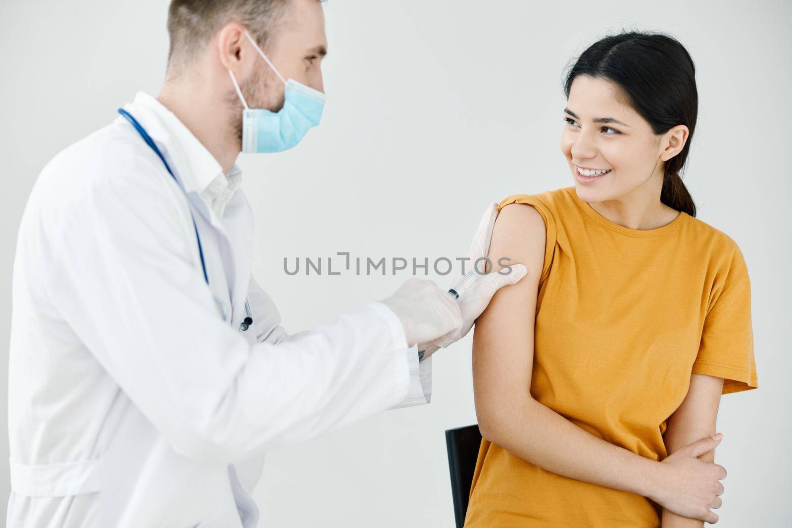 doctor tapes an injection on the shoulder of a happy patient with adhesive tape covid by SHOTPRIME