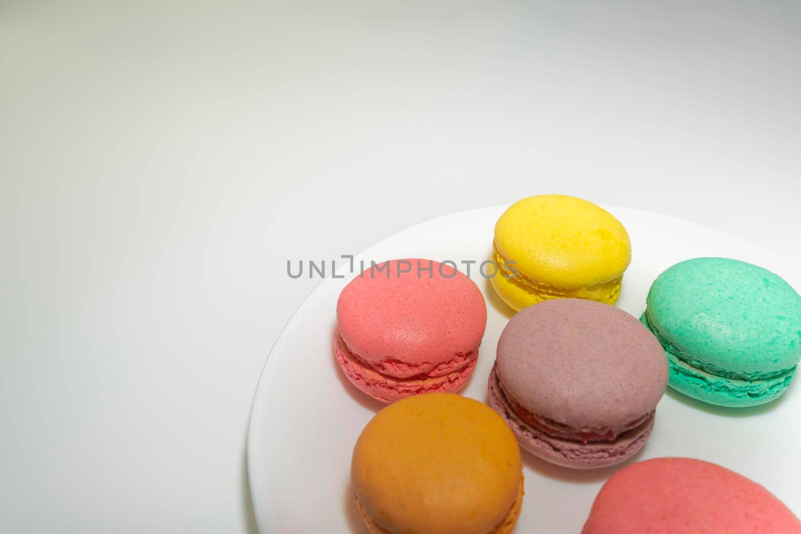multicolored macaroons on a white plate on a gray background. High quality photo