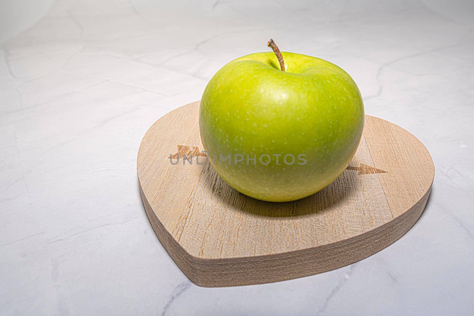 green Apple on the chalkboard in the shape of a heart . photo