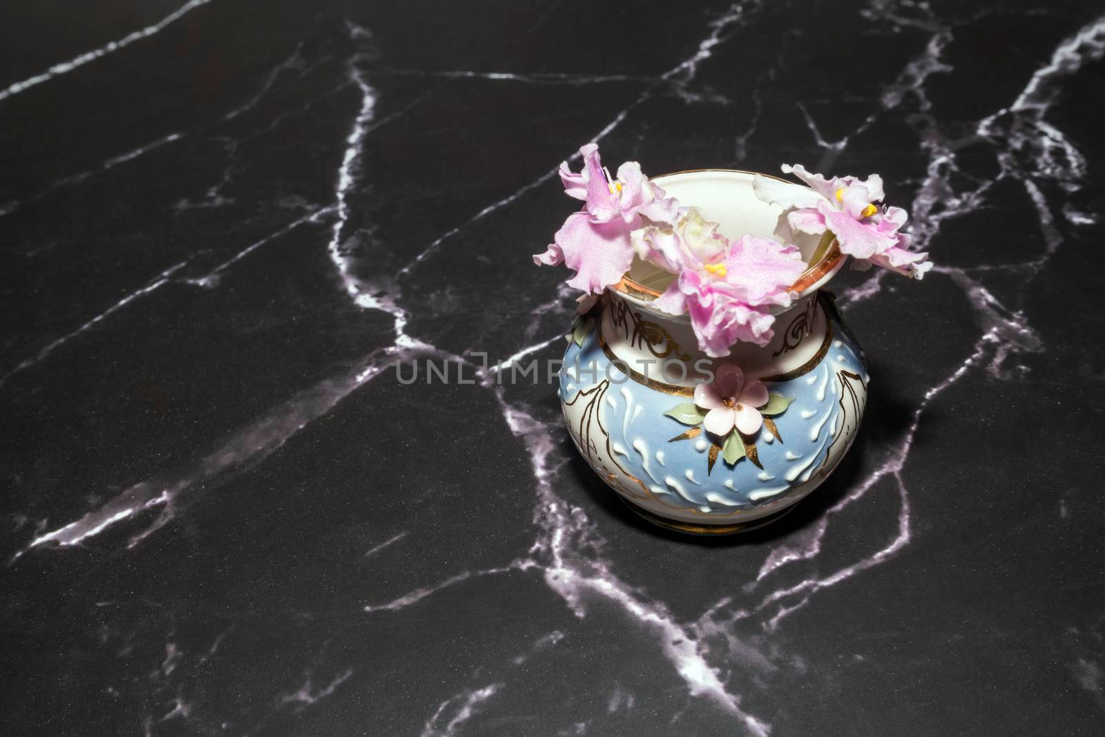 pink violets in a vase on the marble floor. High quality photo