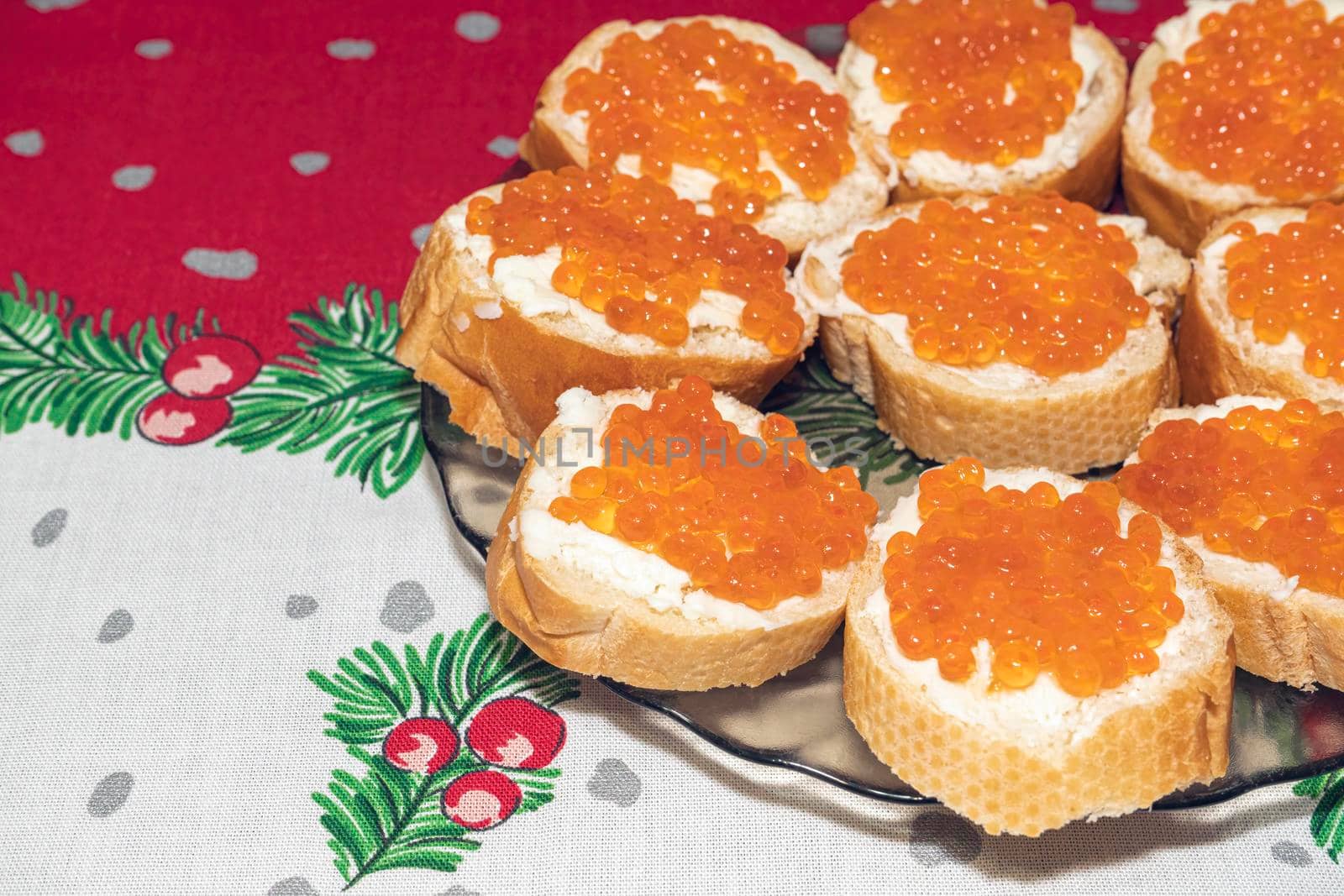 a plate of sandwiches with red caviar on a New Year's tablecloth. High quality photo