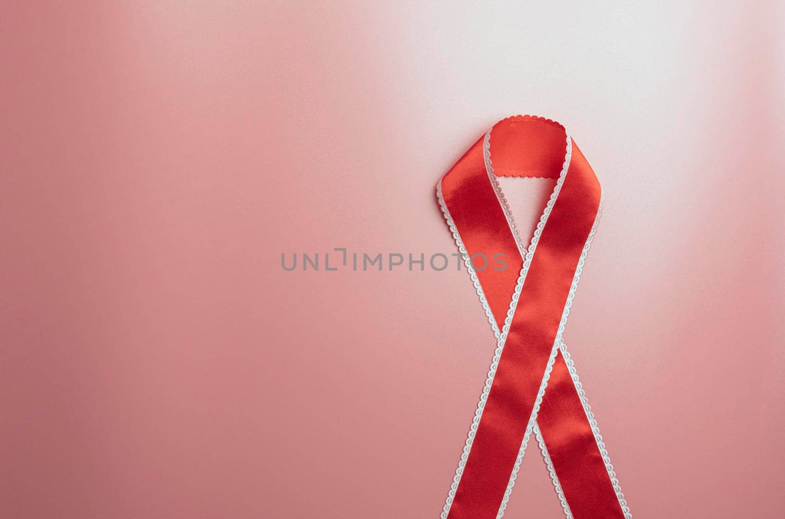 red ribbon for AIDS day on a red background. the view from the top. High quality photo