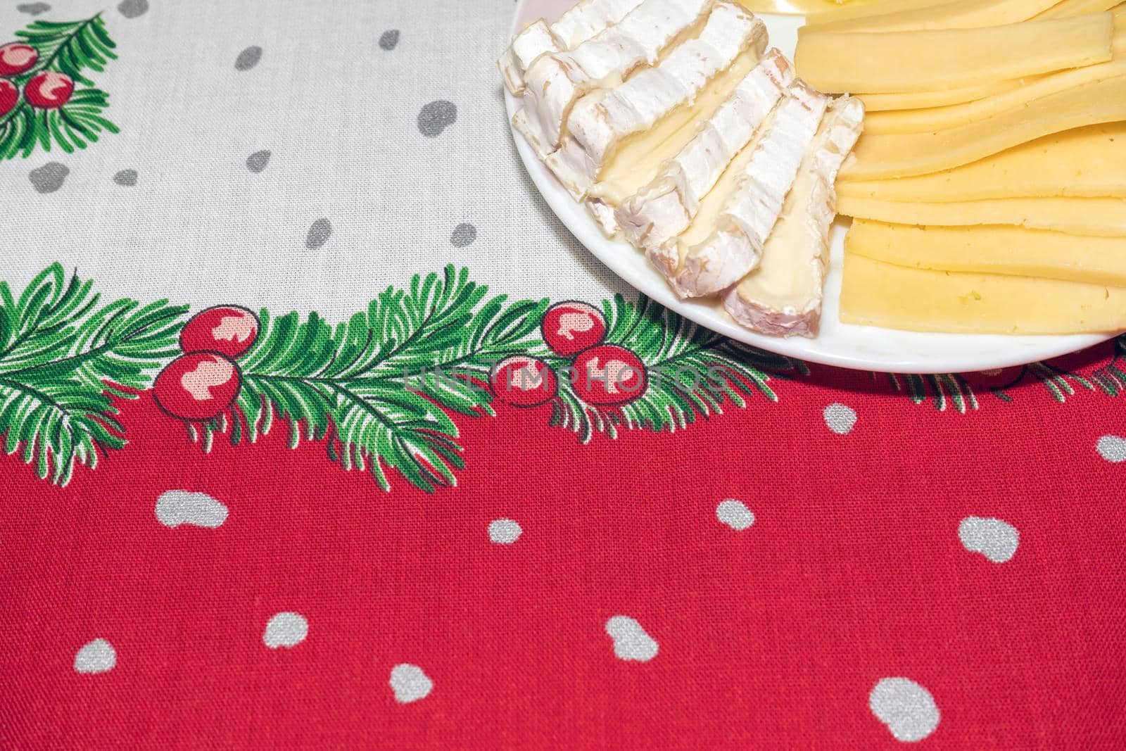 a plate of the sliced cheese on a New Year's tablecloth. High quality photo