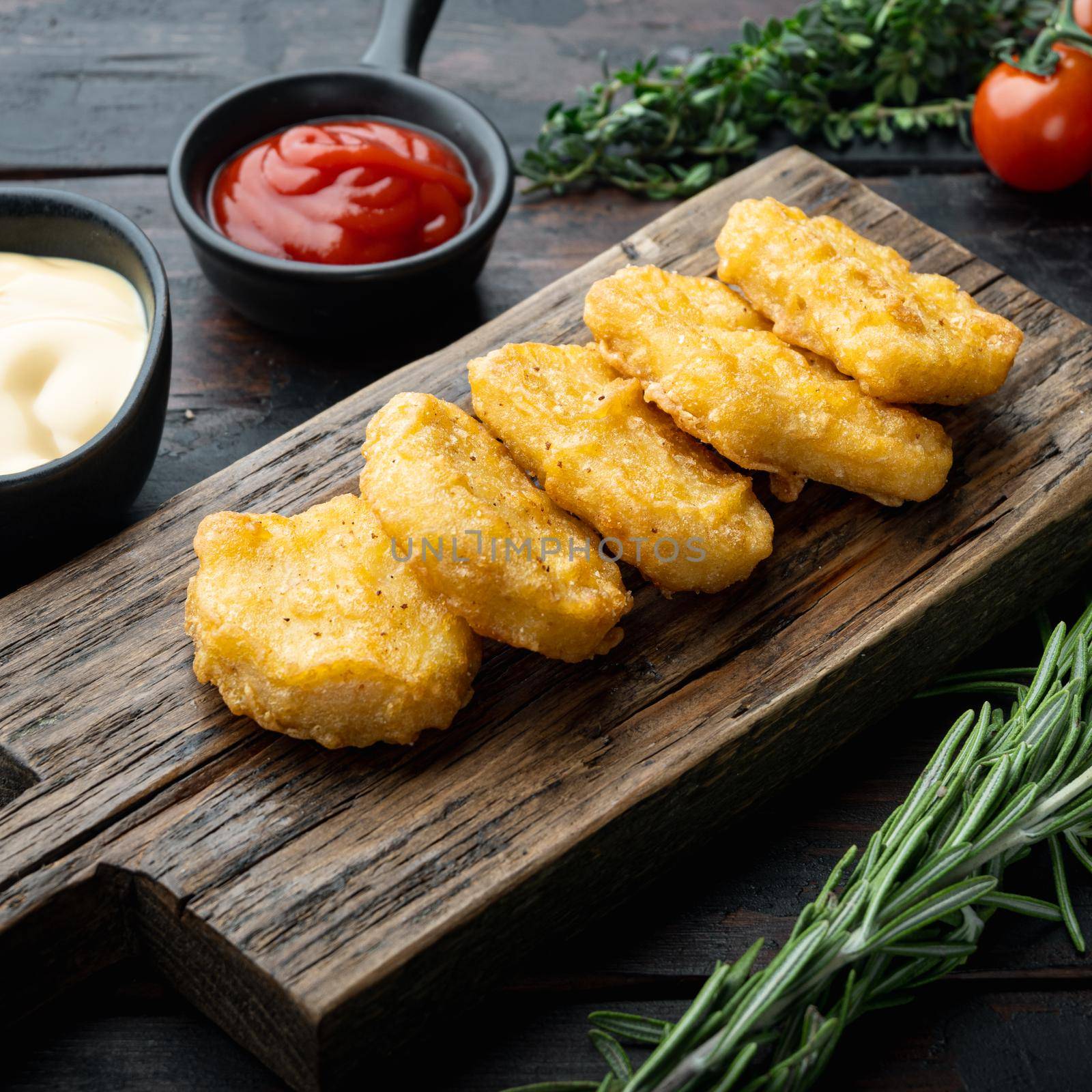 Fried crispy chicken nuggets meat on dark wooden background.