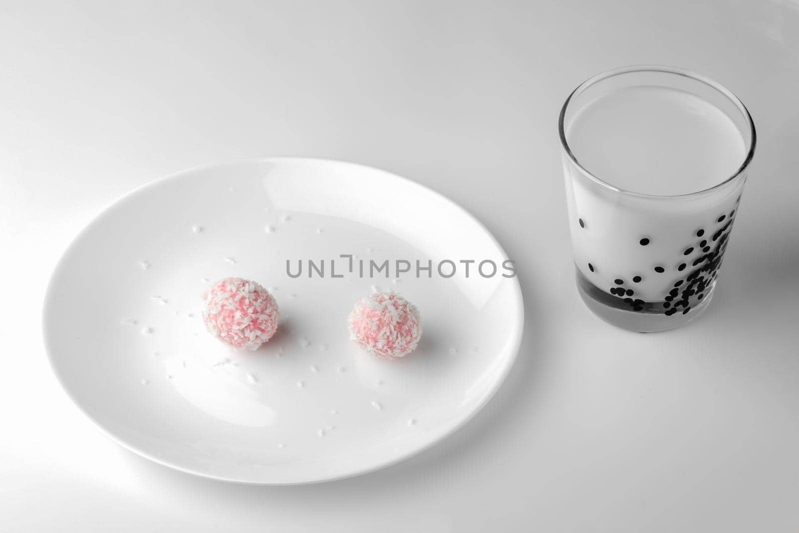 pink chocolate candy and a glass of milk on a white background. candy ball macro. isolate. High quality photo