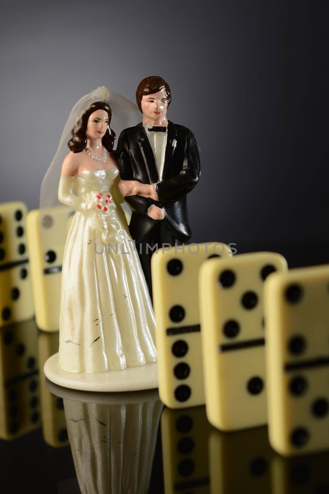 The domino effect of marriage concept utilized by a wedding cake topper.