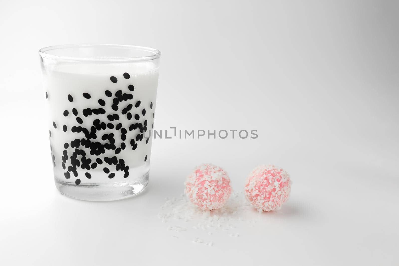 pink chocolate candy and a glass of milk on a white background. candy ball macro. isolate. High quality photo