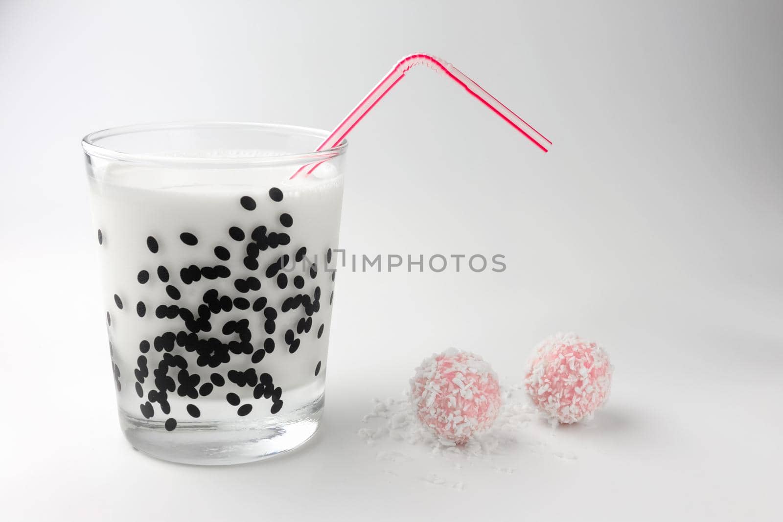 pink chocolate candy and a glass of milk on a white background. candy ball macro. isolate. High quality photo