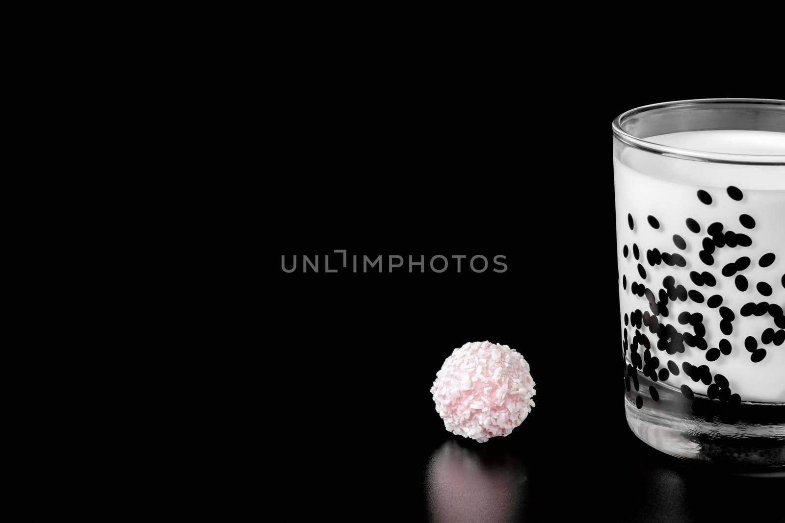 a glass of milk and pink candy on a black background. health food. isolate. High quality photo