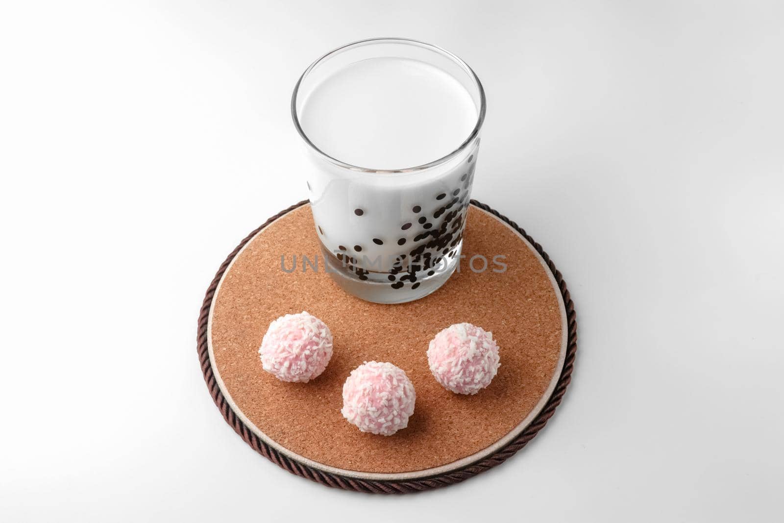 pink chocolate candy and a glass of milk on a white background. candy ball macro. isolate. High quality photo