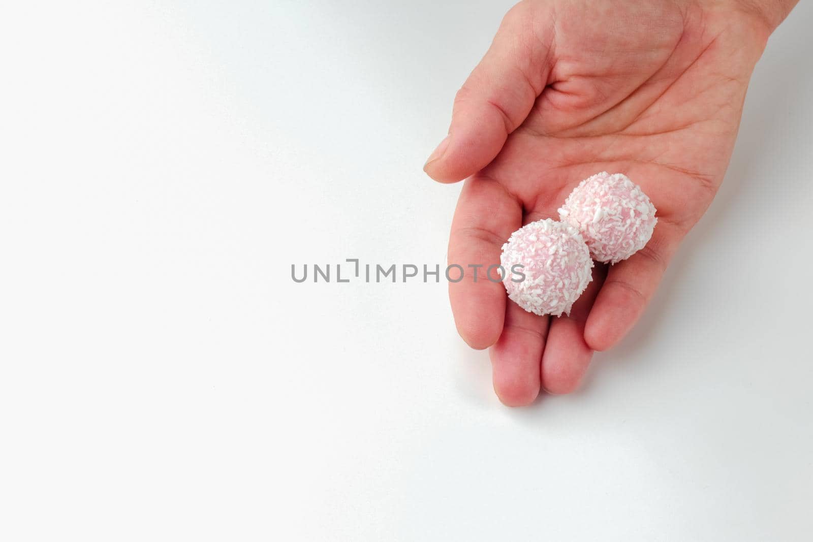 pink chocolate candy in hand on a white background. candy ball macro. isolate. High quality photo
