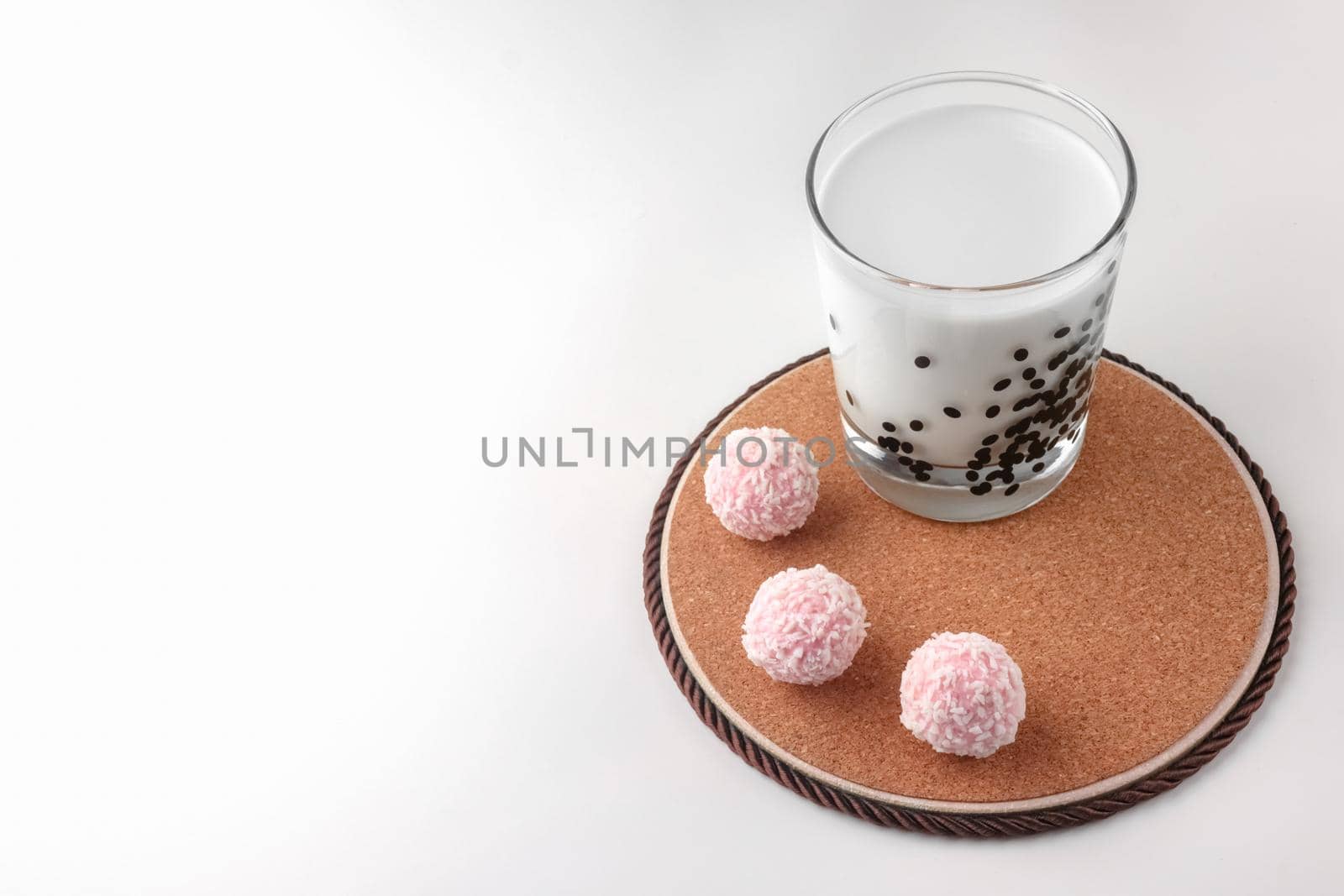 pink chocolate candy and a glass of milk on a white background. candy ball macro. isolate. High quality photo