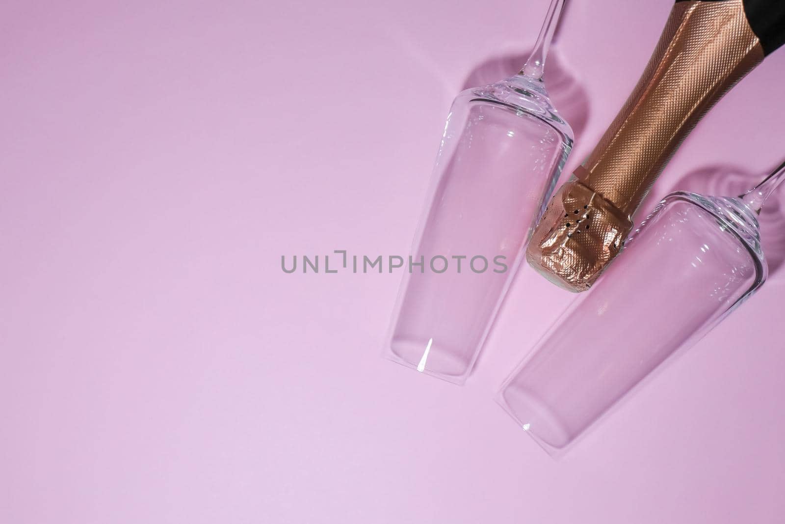 bottle of champagne with glasses on a pink background. high-quality photos