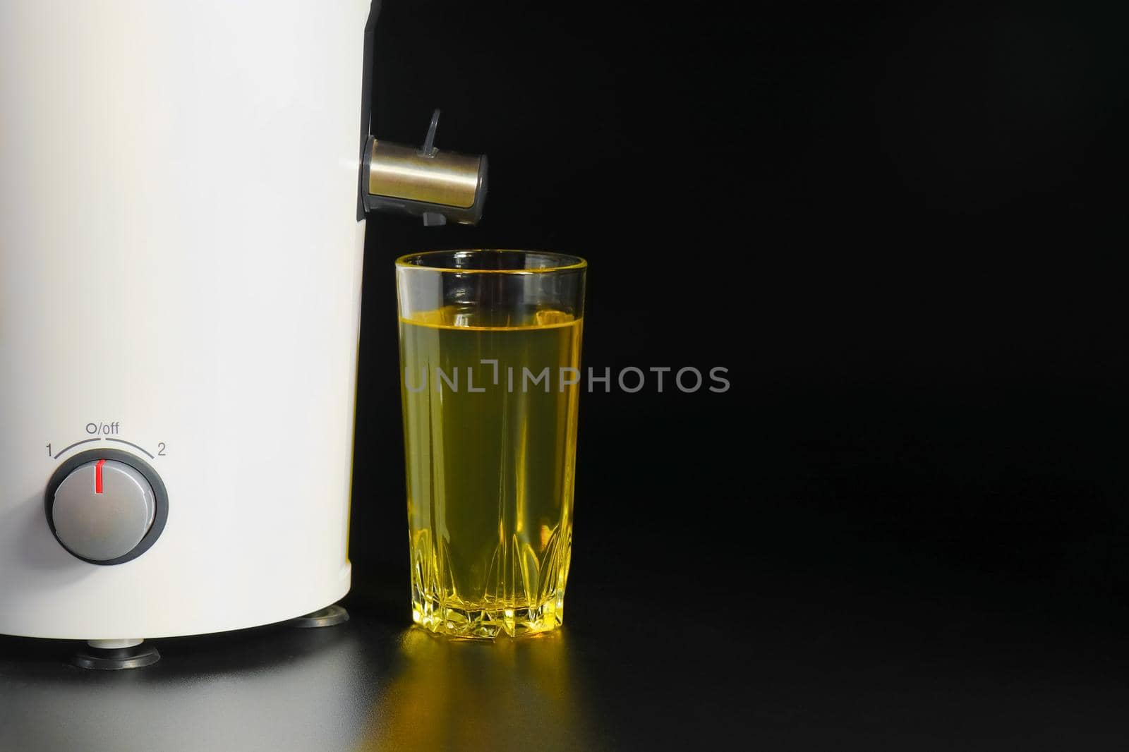 a glasa glass of juice and a juicer on black backgrounds of juice and a juicer on black background. High quality photo