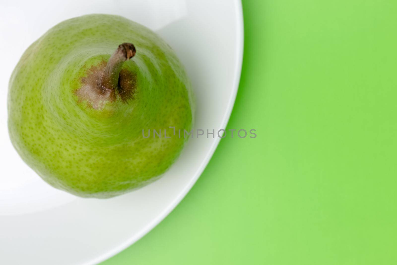 pear on a plate on a green background close-up. High quality photo