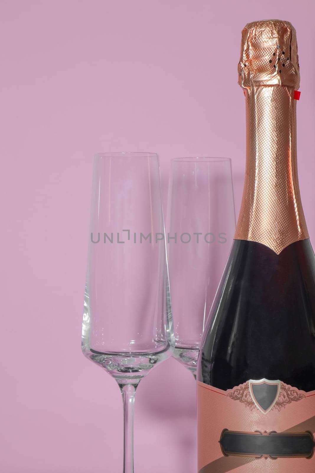 bottle of champagne with glasses on a pink backgroun . High quality photo