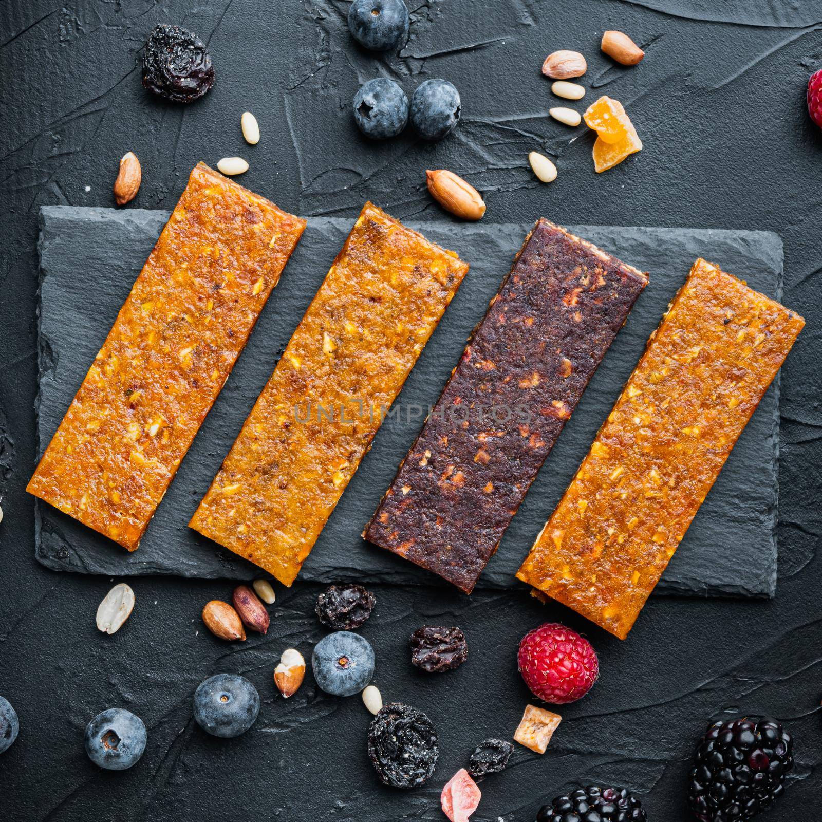 Fruit berry and nut energy bars, healthy snack, top view,on black background by Ilianesolenyi