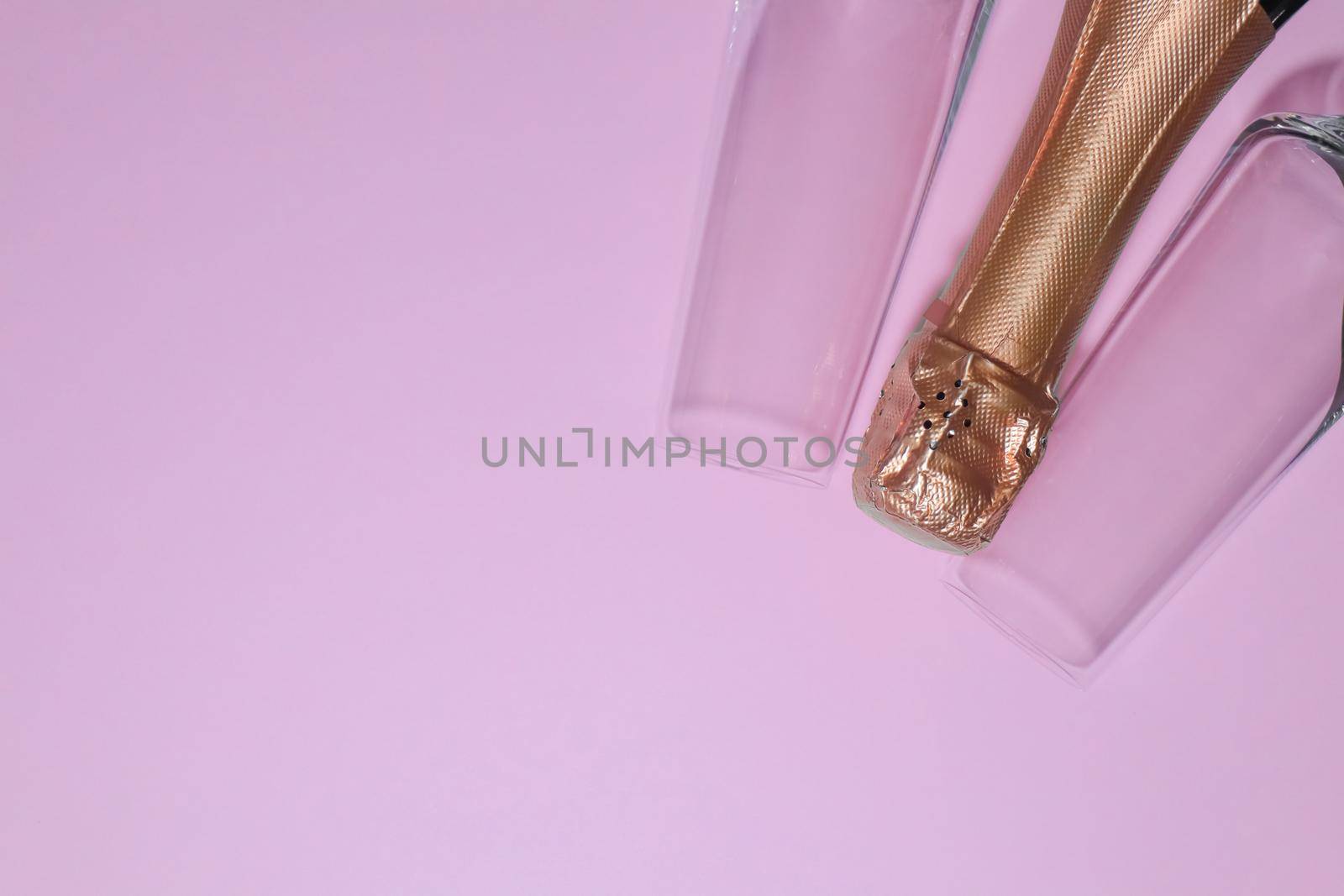 bottle of champagne with glasses on a pink backgroun . High quality photo