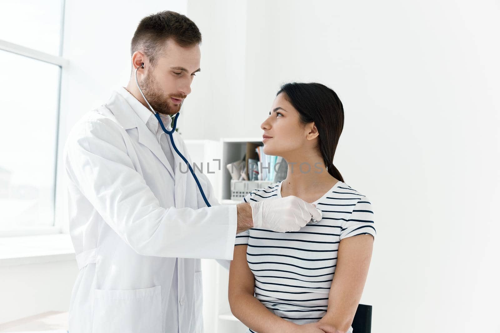 male doctor in white coat examining female patient in hospital. High quality photo