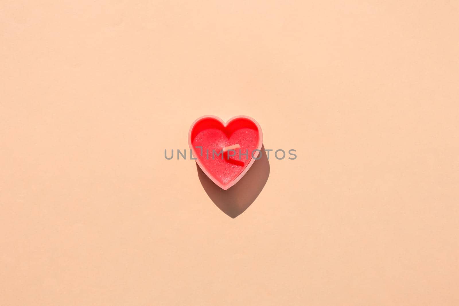 heart-shaped candle on a brown background. hard shadow. isolate. High quality photo