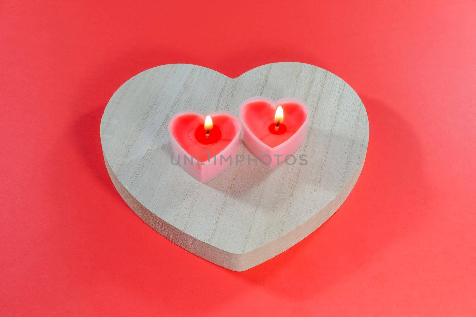 pink candles in the form of a heart on a red background for Valentine's day . High quality photo