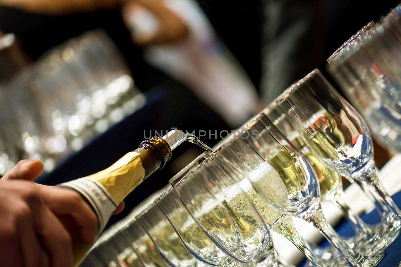 Bartender pouring champagne into glasses at party.