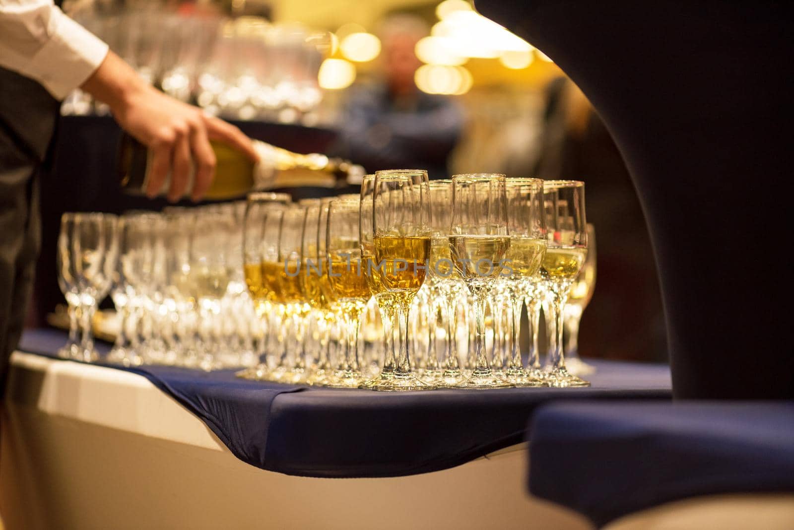 Bartender pouring champagne into glasses at party.