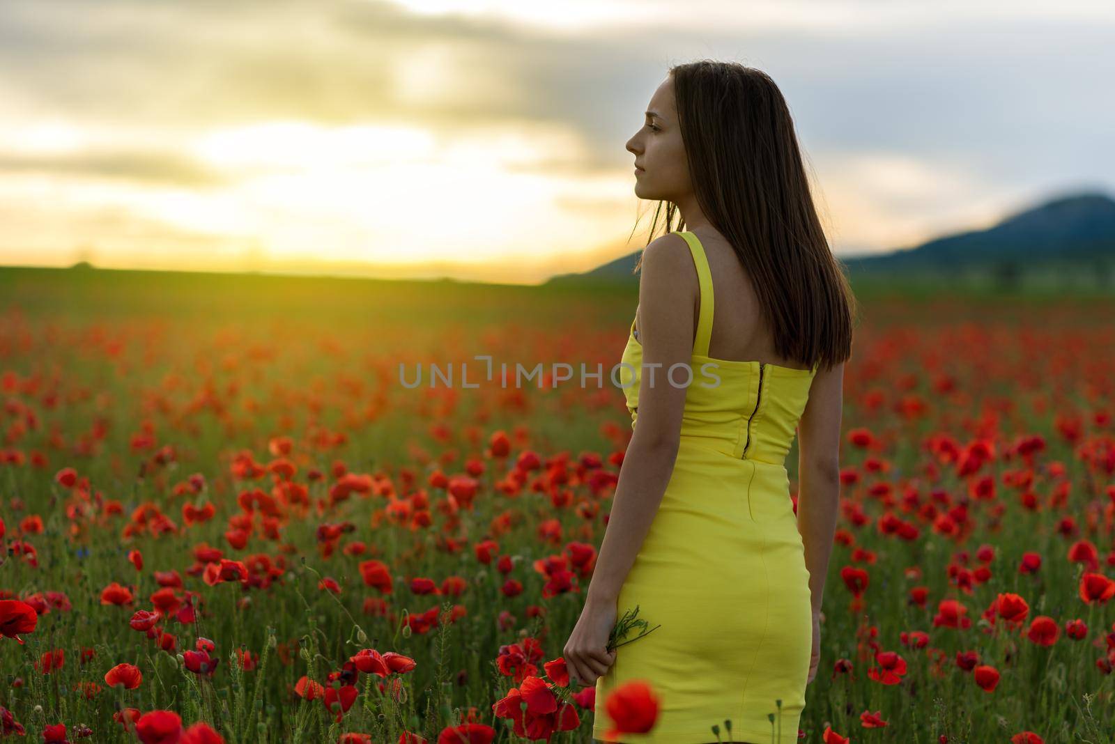 Woman in yellow dress standing in field of poppies