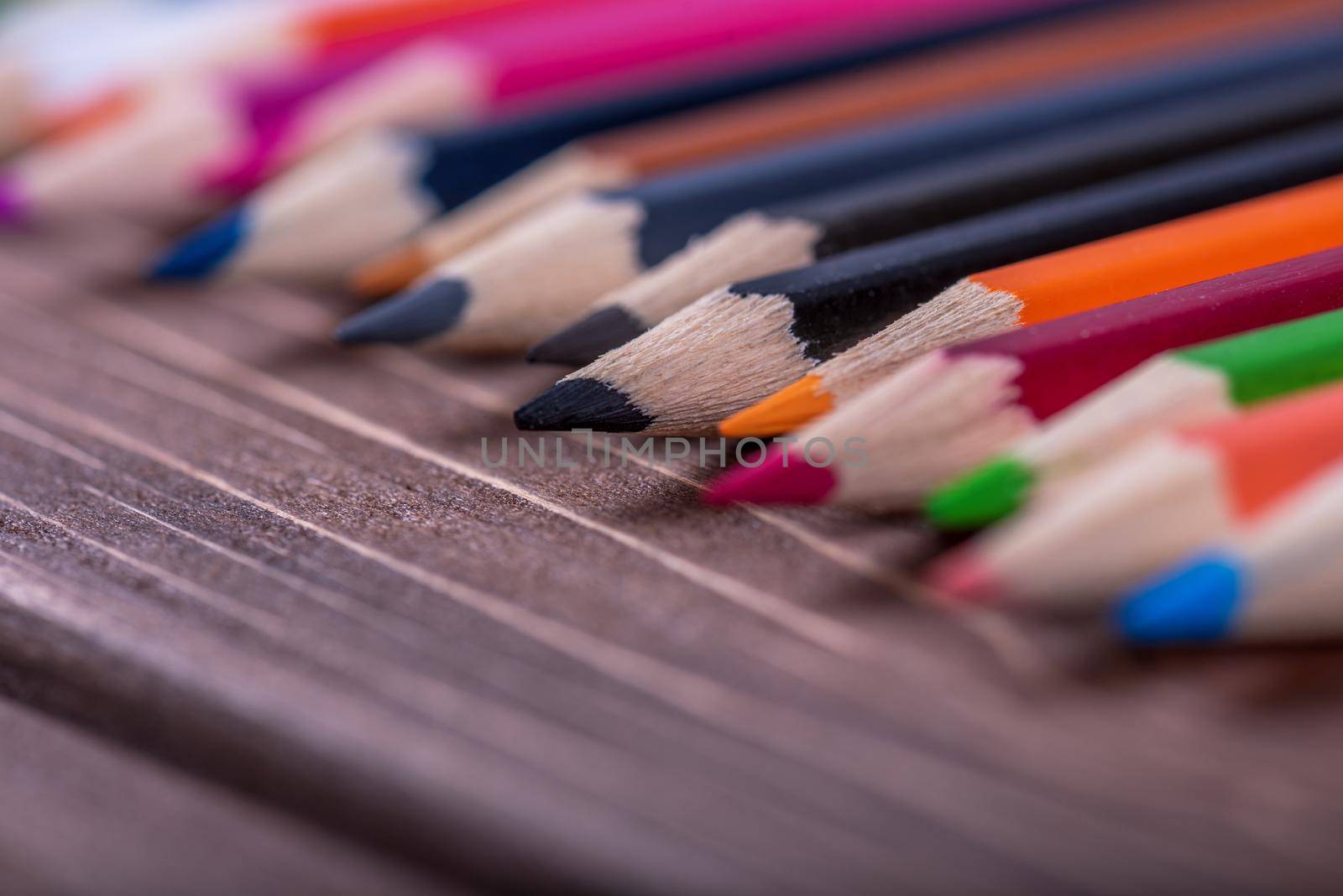 Colored multi colored pencils close up macro down on a vintage wooden background.
